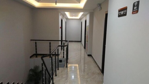 Un couloir d’hôtel avec un escalier, un luminaire au plafond et un panneau indiquant la disponibilité du Wi-Fi.