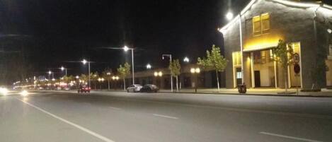 Une rue de nuit avec un immeuble sur la droite.