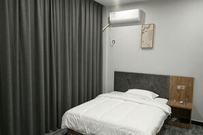 A hotel room with a bed, a nightstand, a wall-mounted air conditioner, and a curtain. - Nancheng Xilaike Hotel (Nancheng)