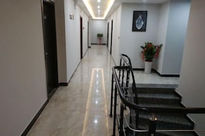 Un corridoio d'albergo con una scala, una ringhiera e una pianta in vaso.