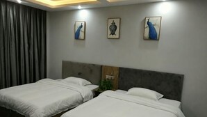 Une chambre d’hôtel avec deux lits, une tête de lit grise et trois œuvres d’art accrochées au mur.