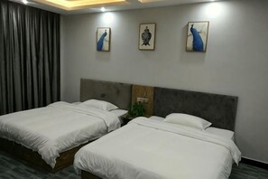 Een hotelkamer met twee bedden, een grijze hoofdbord en drie kunstwerken aan de muur.