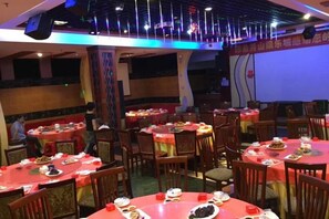 Un restaurante con mesas y sillas redondas, algunas mesas con platos.