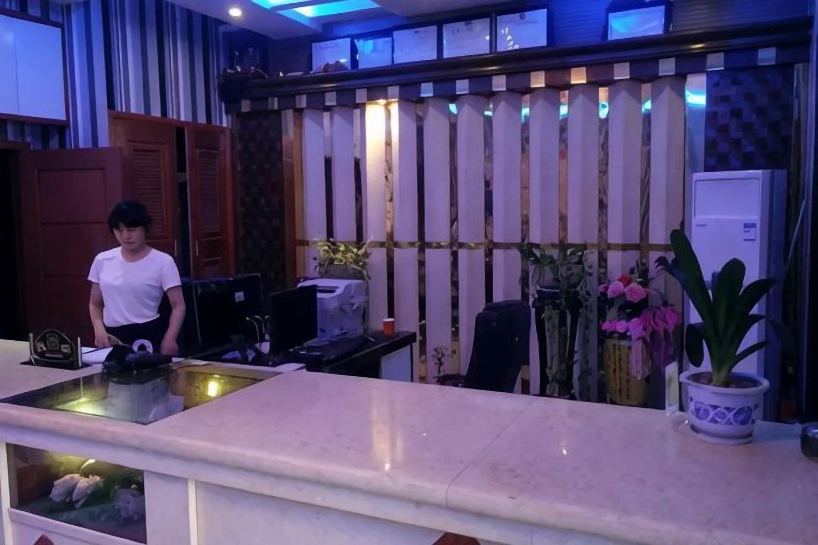 A reception desk with a computer, a plant, and a potted plant.
