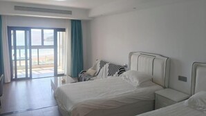 Et hotelværelse med en stor seng, et natbord, en stol og udsigt til det fri gennem en skydedør.