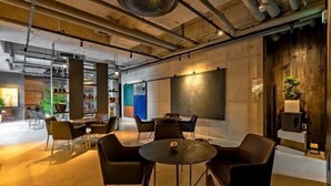 A modern interior with a round table and chairs, a large blackboard, and a wooden accent wall. - Ingu Stay (Yangyang)