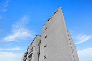 A tall, white building with a sloped roof and multiple windows.