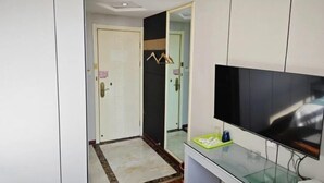 A modern bathroom with a large mirror, a television, and a small shelf with toiletries. - NANYUAN INN (Cixi Sanbei East Road) (Cixi)