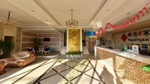 A hotel lobby with a reception desk, a chandelier, a decorative column, and a seating area with a sofa and chairs. - NANYUAN INN (Cixi Sanbei East Road) (Cixi)