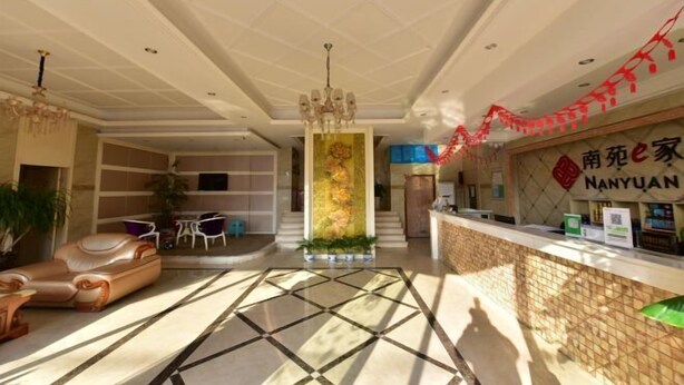 A hotel lobby with a reception desk, a chandelier, a decorative column, and a seating area with a sofa and chairs. - NANYUAN INN (Cixi Sanbei East Road) (Cixi)