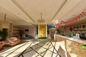 A hotel lobby with a reception desk, seating area, and a decorative column. - NANYUAN INN (Cixi Sanbei East Road) (Cixi)