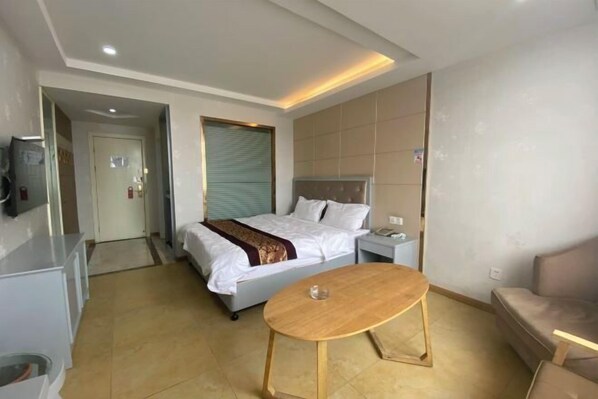 A hotel room with a bed, bedside table, and a small round table.