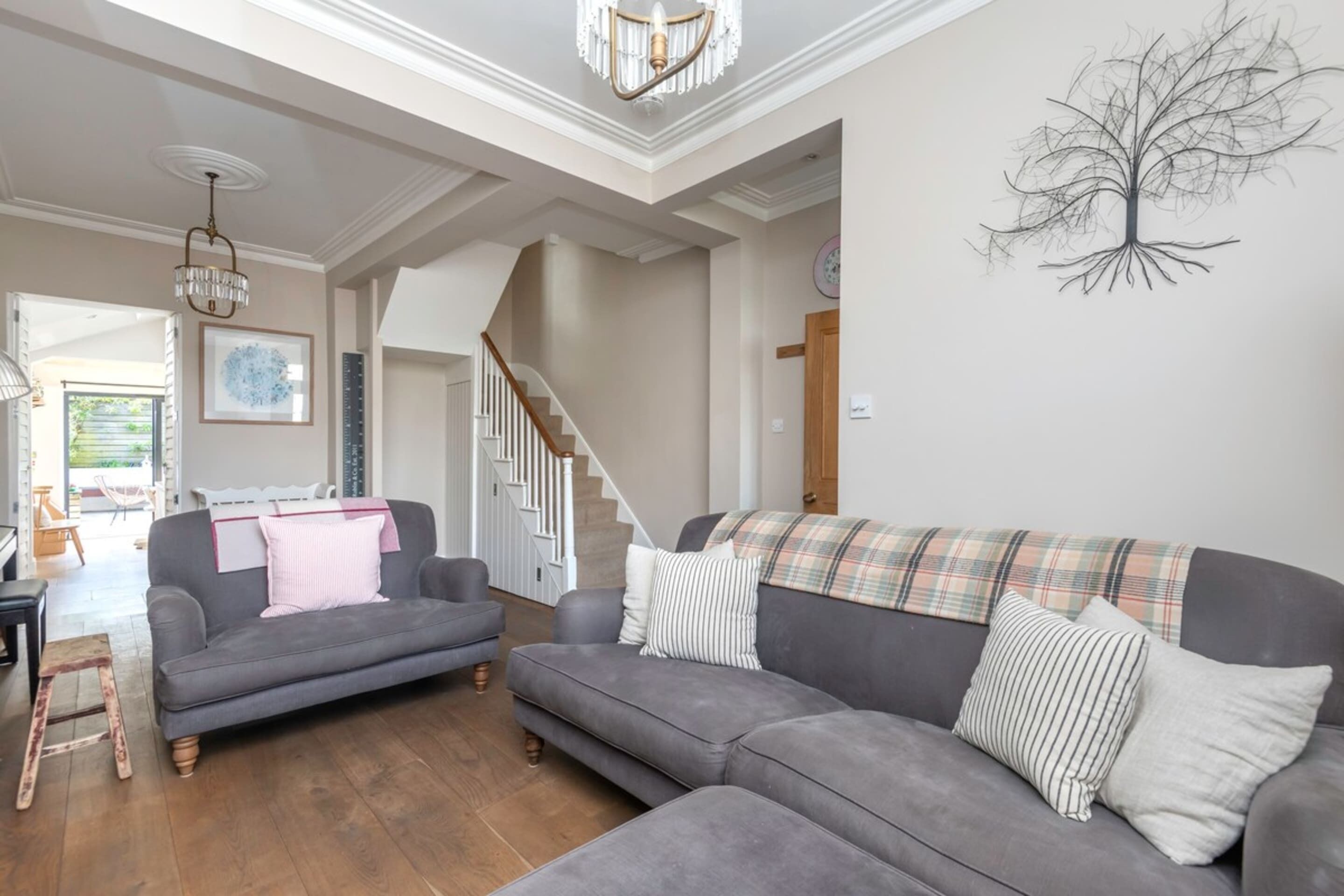 Un salon avec un canapé gris, une échelle en bois et un escalier menant à un autre niveau.