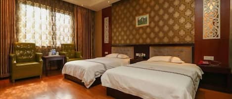 Habitación de hotel con dos camas, un sillón verde, una mesita y un adorno en la pared.