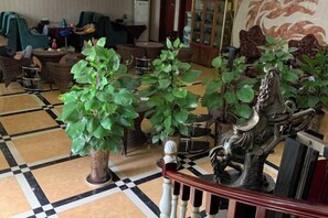 A lobby with a checkered floor, potted plants, and a decorative metal sculpture. - Panzhihua Kaidikangyang Hotel (Panzhihua)