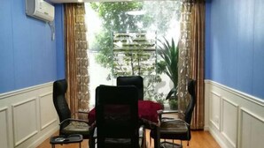 Une pièce avec un mur bleu, un plancher en bois, une table recouverte d’une nappe rouge et quatre chaises.