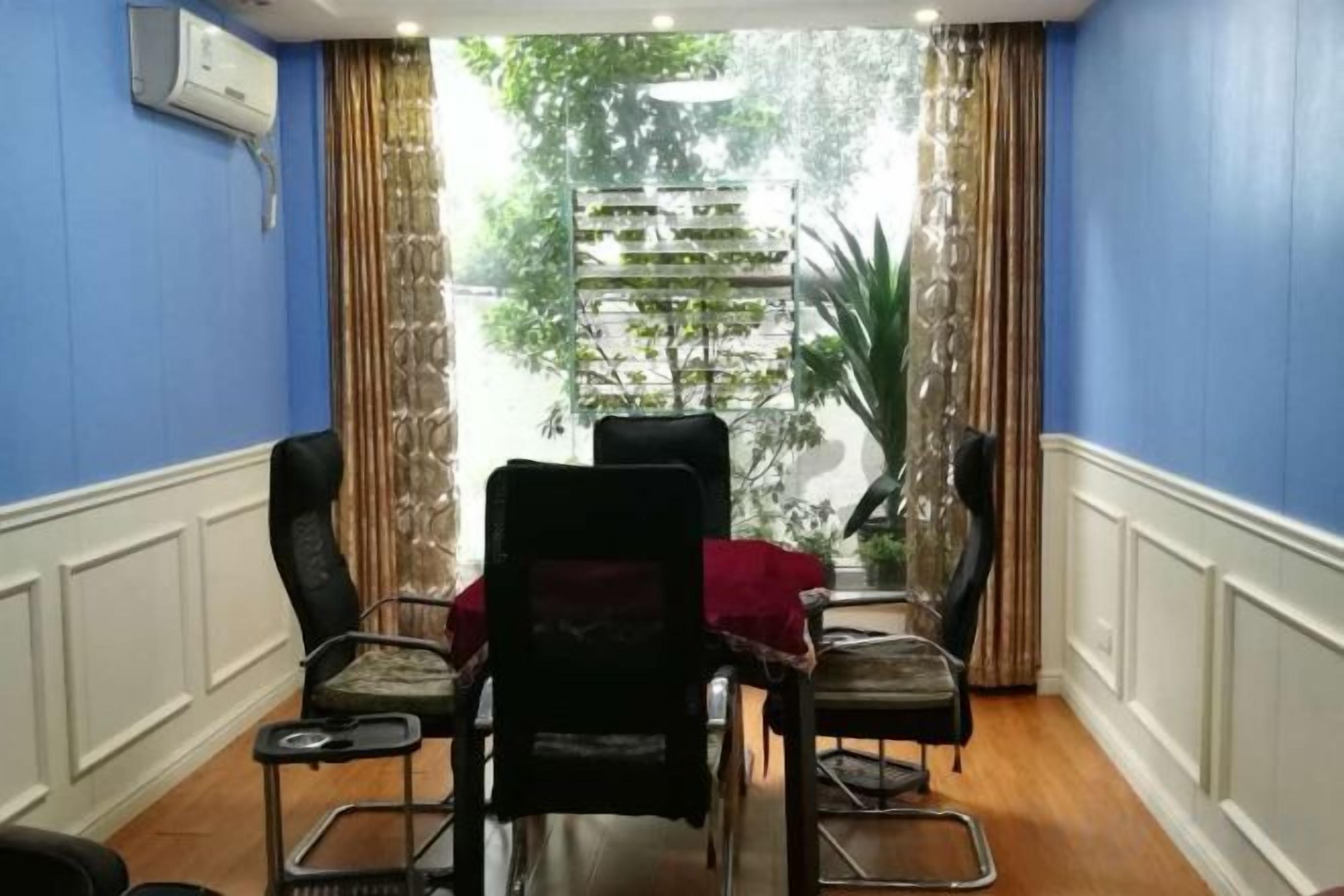A conference room with a table and chairs, a view of a building through a window, and a plant in the corner.