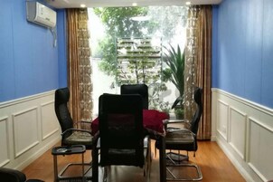 A conference room with a table and chairs, a view of a building through a window, and a plant in the corner.
