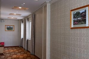 A hotel corridor with patterned carpet, a reception desk, and a framed picture on the wall. - Panzhihua Kaidikangyang Hotel (Panzhihua)