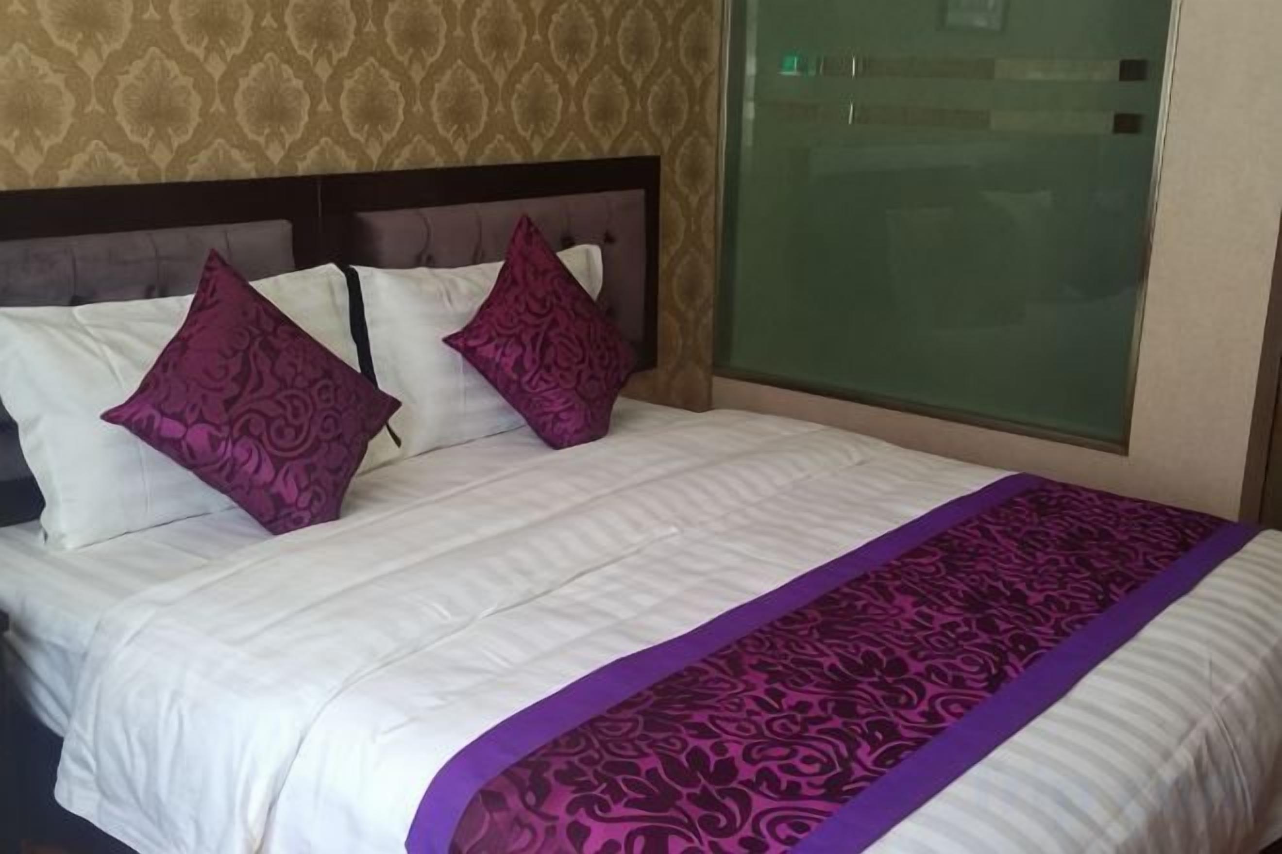 Een bed met een beddekleed met patroon en twee decoratieve kussens.