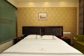 A hotel room with a large bed, a headboard, a nightstand, a green chair, and a wall with a patterned wallpaper. - Panzhihua Kaidikangyang Hotel (Panzhihua)