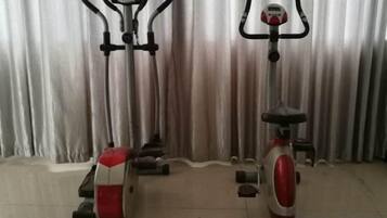 Two stationary bikes in a room with a curtain backdrop.