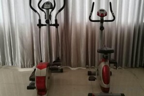 Two stationary bikes in a room with a curtain backdrop. - Panzhihua Kaidikangyang Hotel (Panzhihua)