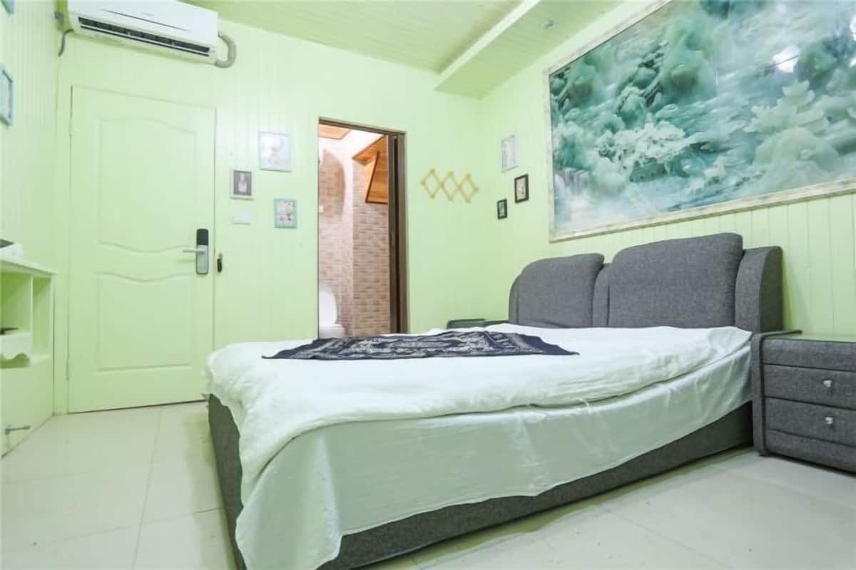 A bedroom with a bed, a dresser, a door, and a wall with a painting.