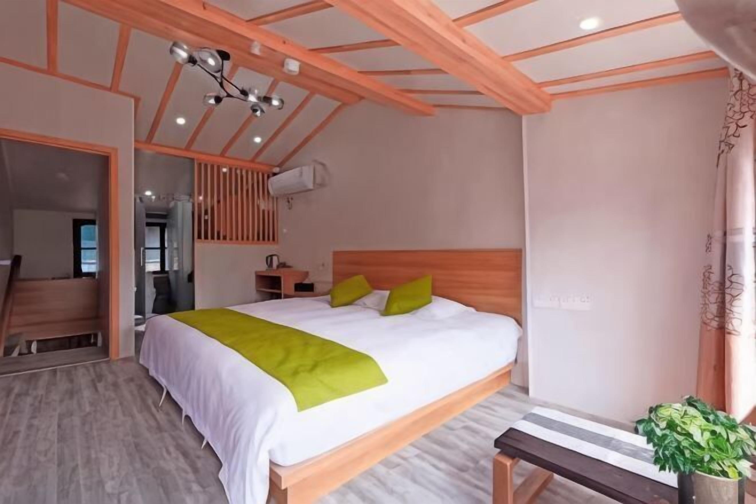 Quarto com cama de madeira, um banco, uma planta em vaso e um ventilador de teto.