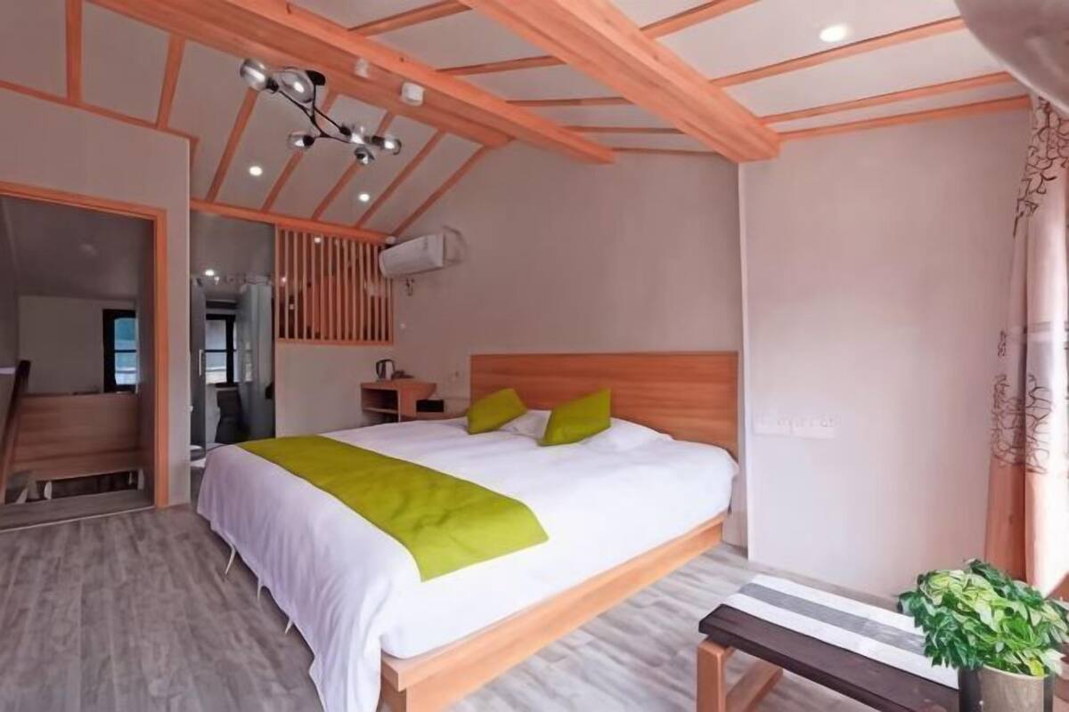 A bedroom with a wooden bed, a bench, a potted plant, and a ceiling fan.