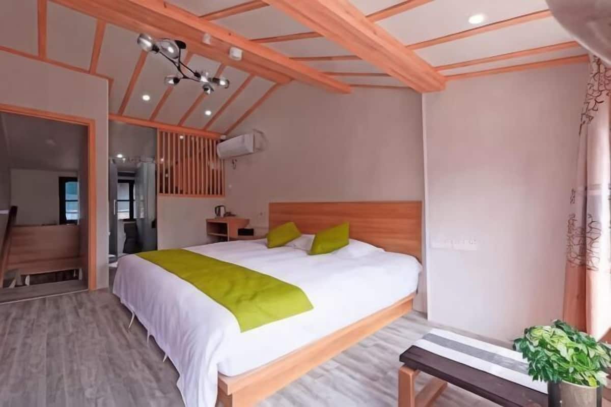Quarto com cama de madeira, um banco, uma planta em vaso e um ventilador de teto.