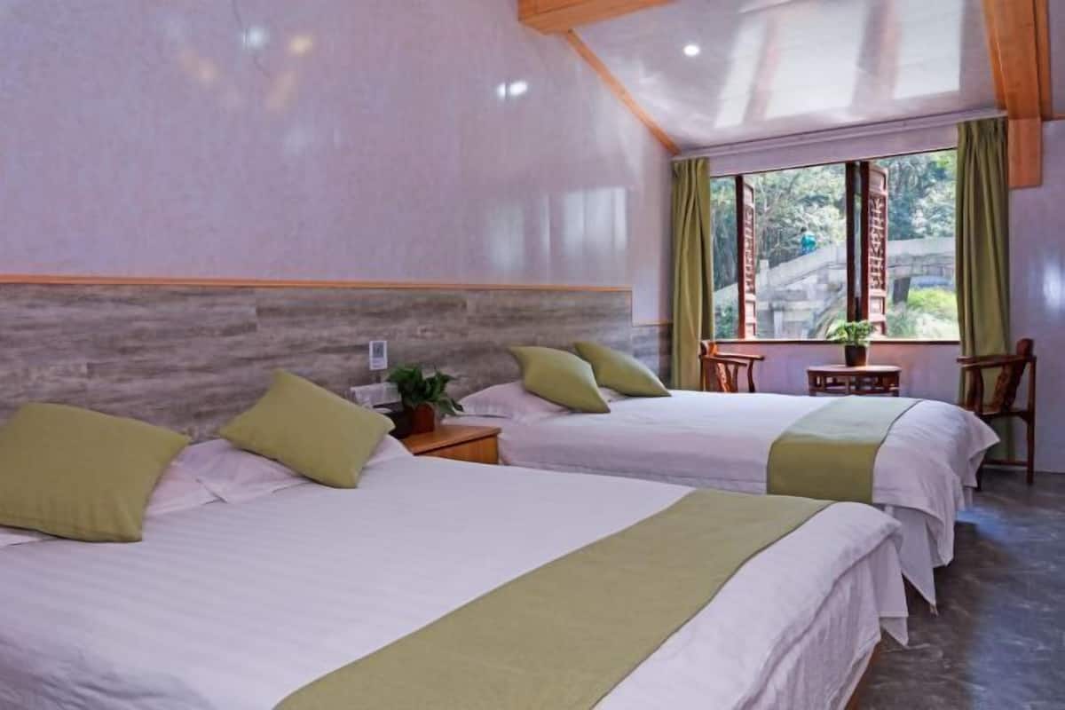 A room with two beds, a small table, and a window with curtains.
