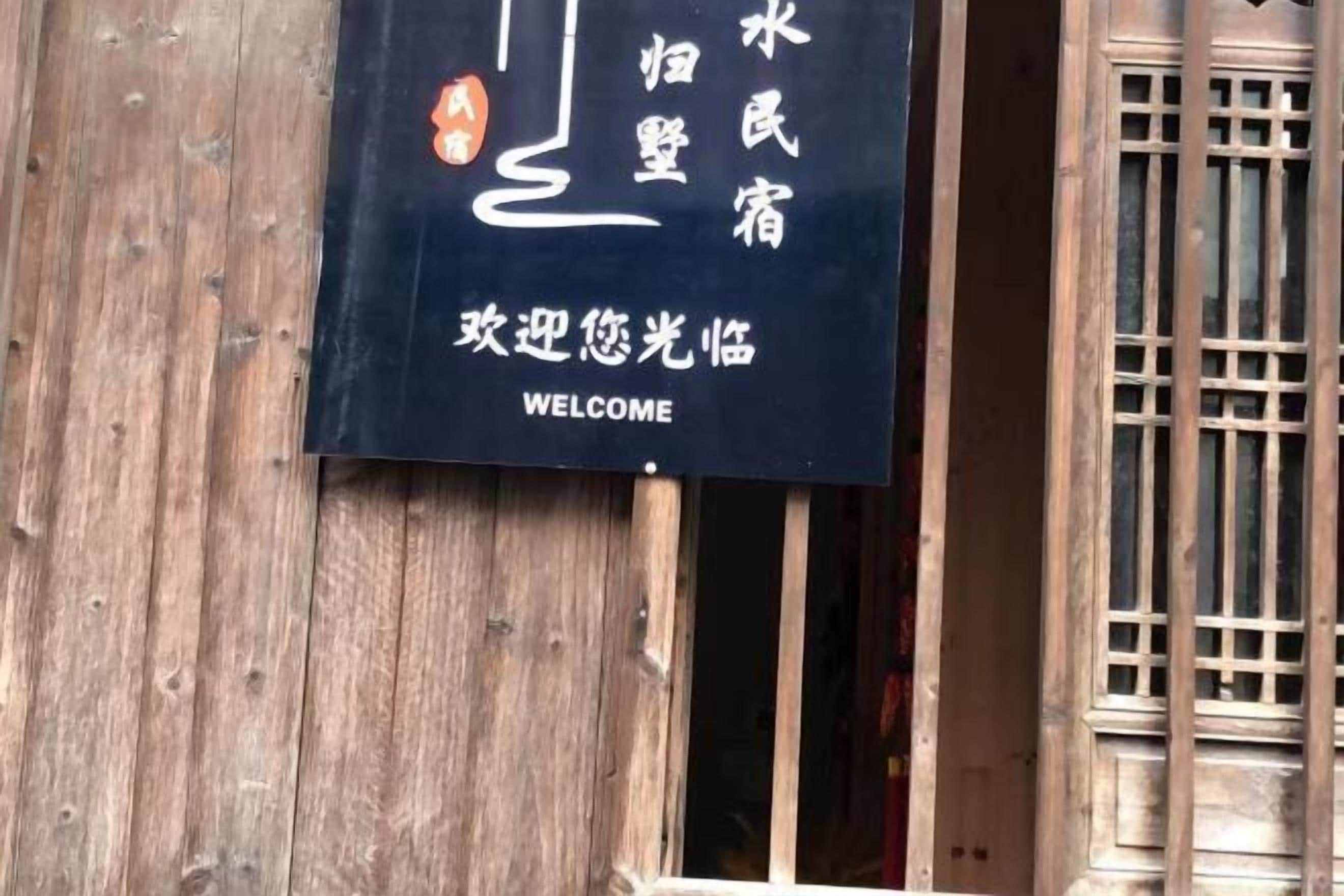 A wooden door with a sign that reads "WELCOME" in English and Chinese characters.