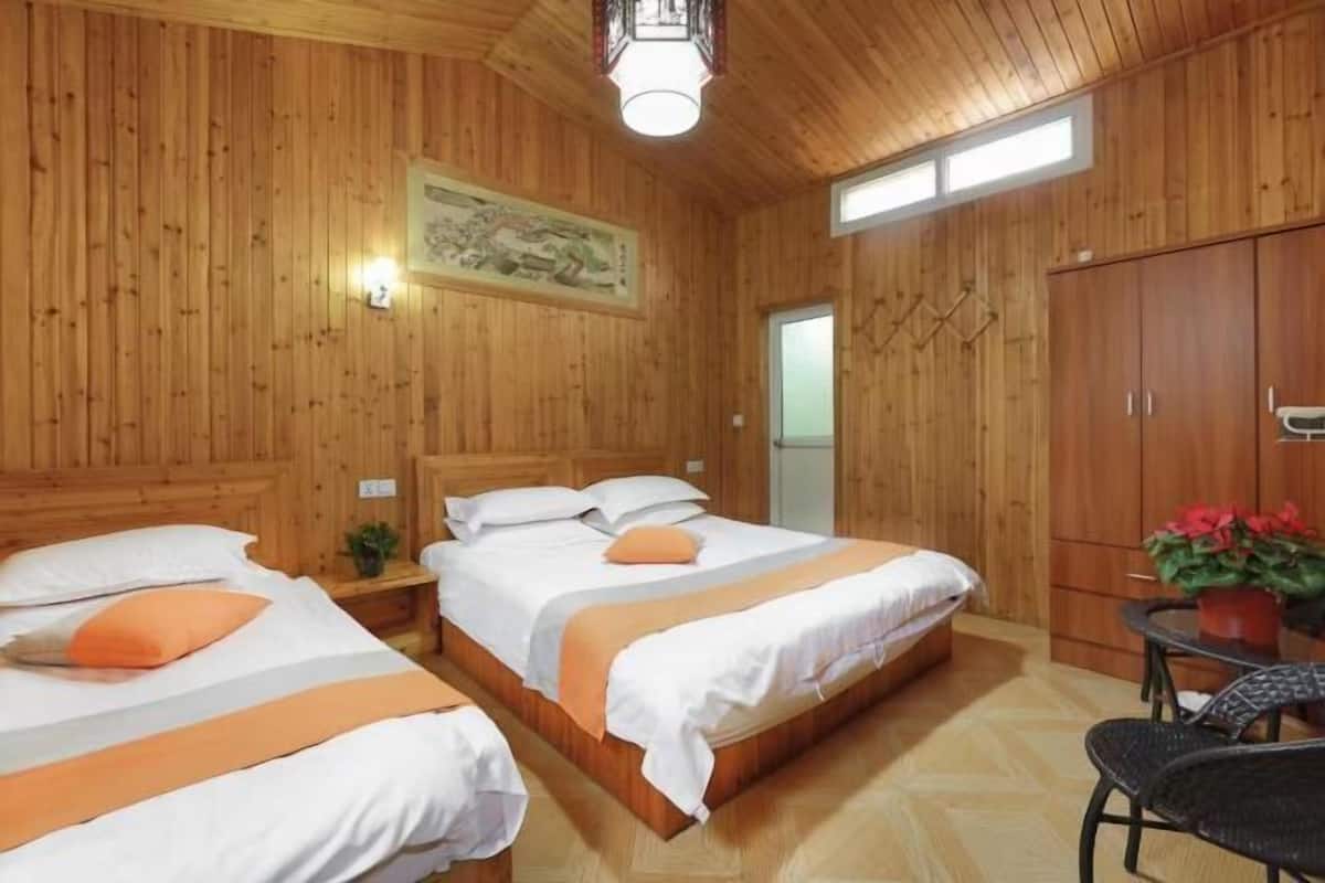 A wooden-paneled room with two beds, a table, and a wardrobe.