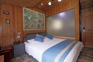 Une pièce aux murs lambrissés, avec un lit, une table de chevet et un grand tableau accroché au mur.