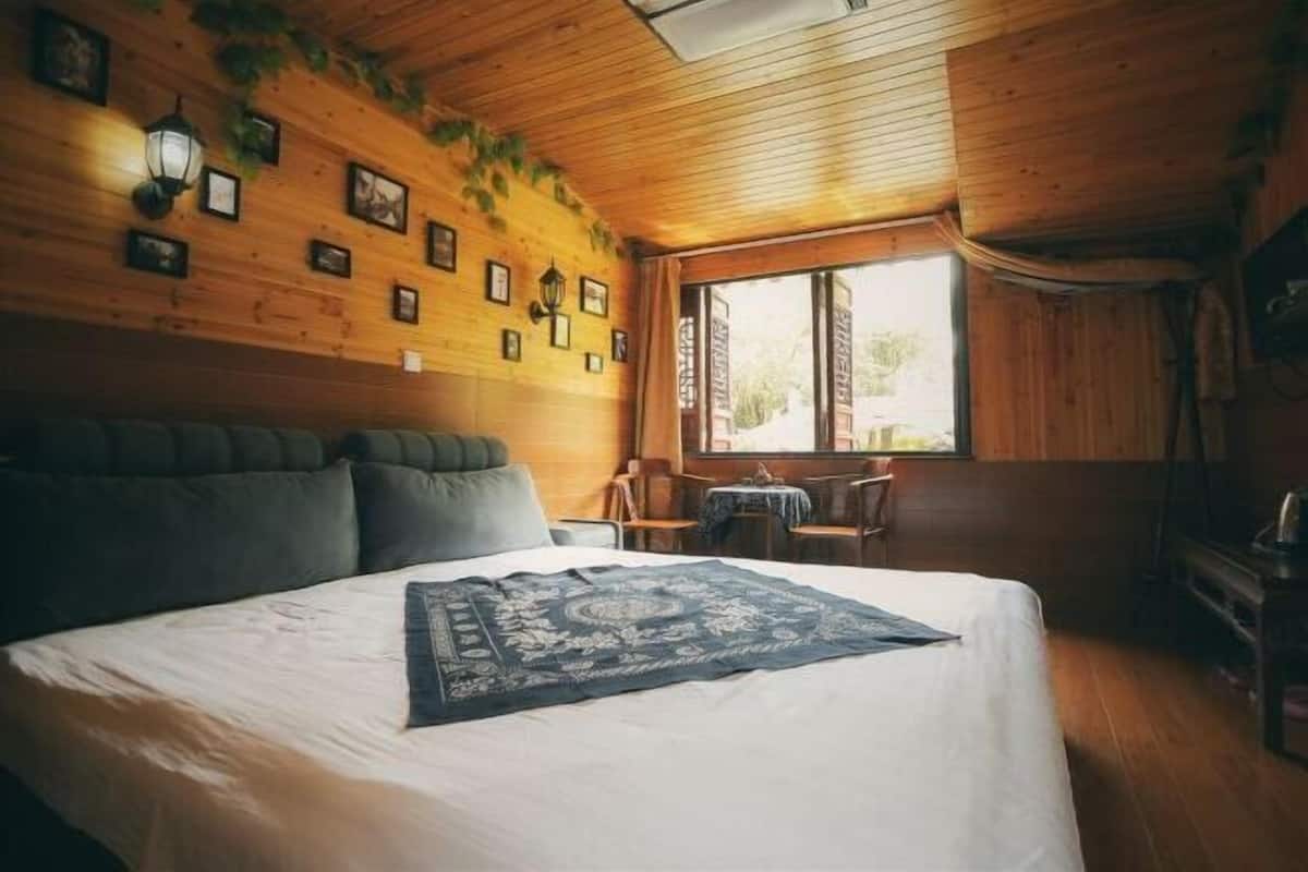 A wooden cabin room with a bed, a small table, and a window.