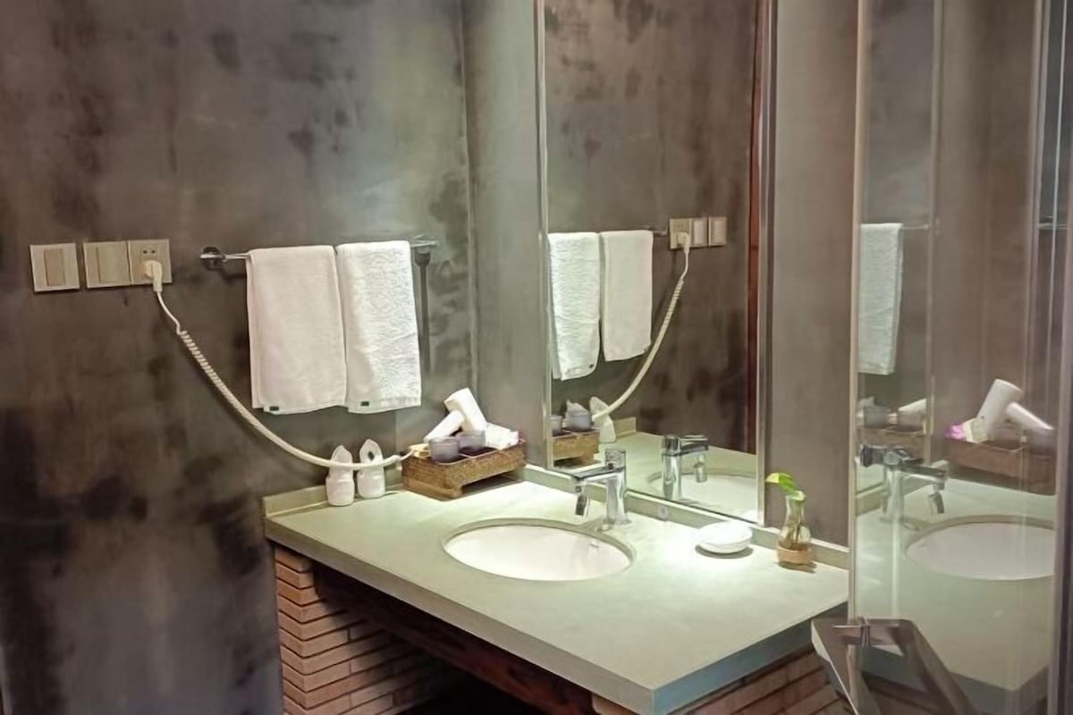 A modern bathroom with a large mirror, two sinks, and a towel rack.