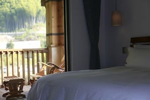A bedroom with a bed, a window with a view of a forest, a wooden chair, and a hanging light fixture. - Two mus of Banvilla Tangquan Meisu (SHISHE Store) (Tonglu)