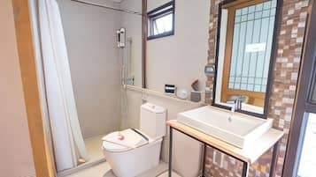 Baño con ducha, inodoro, lavamanos y ventana.