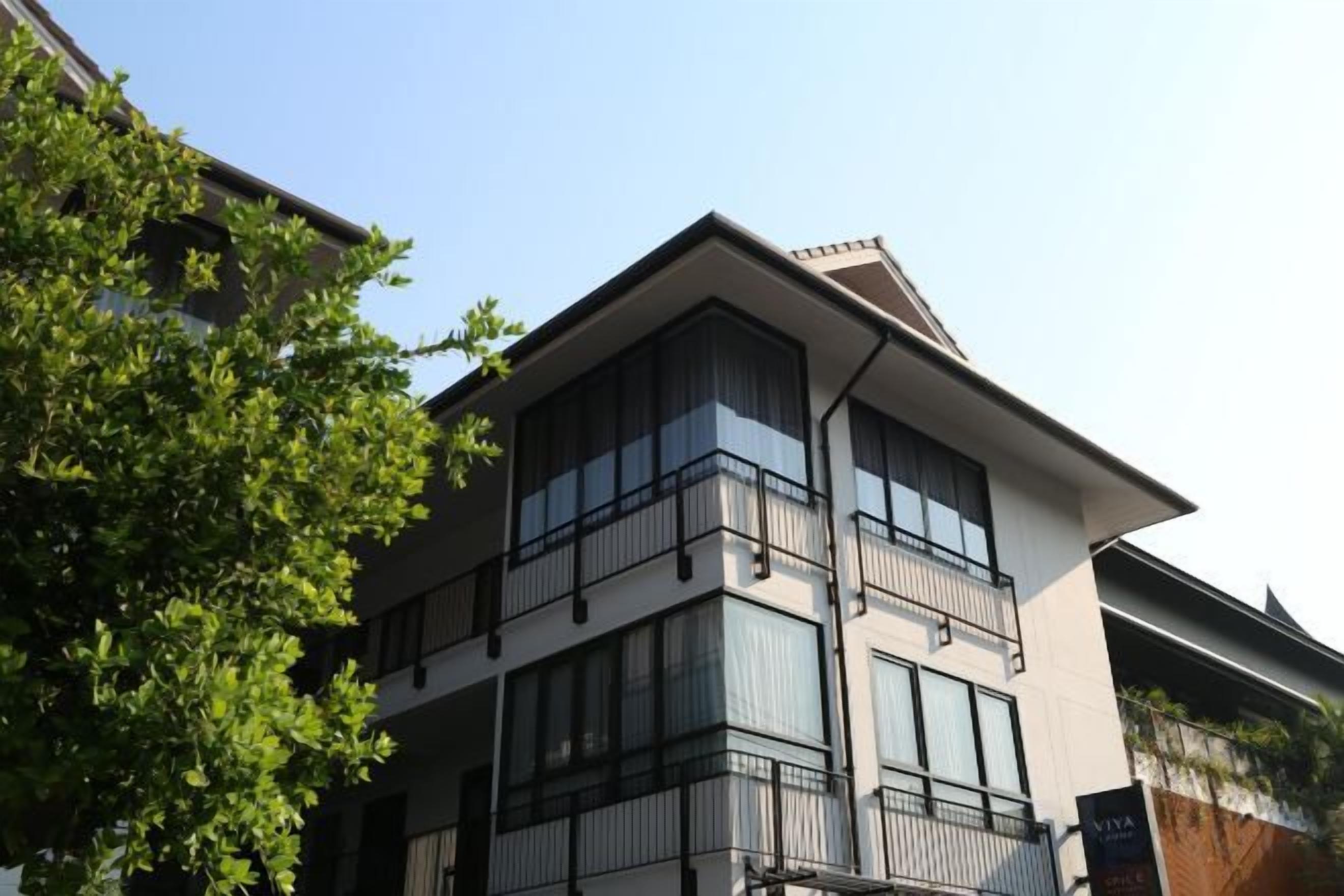 Un edificio de varios pisos con balcones, ventanas amplias y cielo despejado.