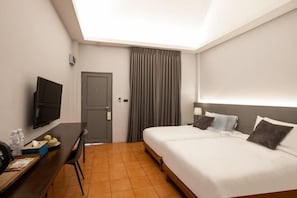 A hotel room with a bed, a desk with a TV, a door, and a window with curtains. - Viya Lodge (Chiang Mai)