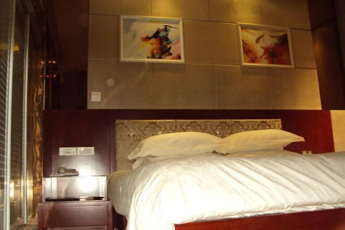 Een hotelkamer met een bed, een nachtkastje en twee ingelijste kunstwerken aan de muur.