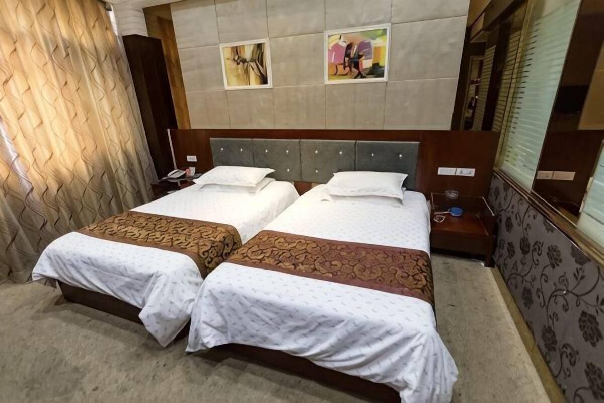 Een tweepersoonsbed met een houten hoofdeinde, twee nachtkastjes en een bijzetbed.