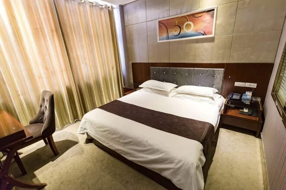 Een hotelkamer met een bed, een bureau, een stoel en een schilderij aan de muur.