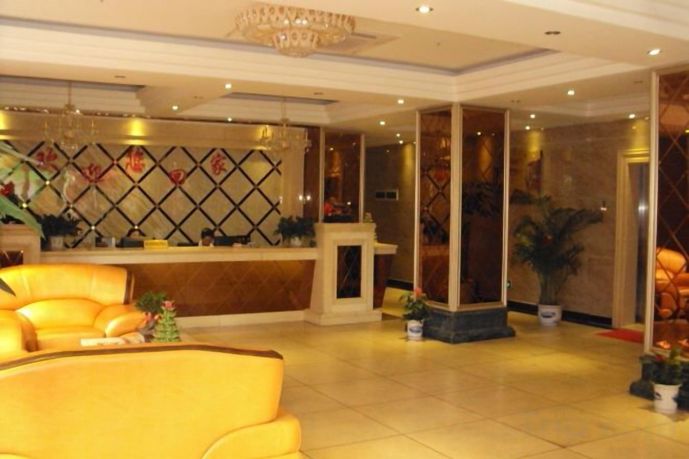 A hotel lobby with a reception desk, a seating area with a sofa, and a decorative wall.