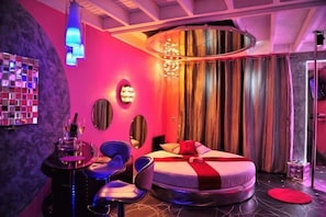A modern bedroom with a circular bed, a round mirror, a chandelier, and a bar area. - Sanya New Xiang Theme Tourism Rental (Sanya)