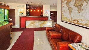 Una zona de recepción con un mostrador rojo, asientos de cuero, un gran mapa mundial y un acuario.