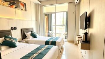 A hotel room with two beds, a television, and a sliding door leading to a balcony.