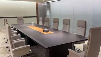 A conference room with a long table, six chairs, and a carpeted floor.