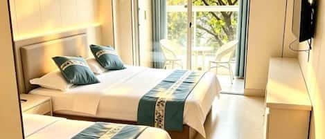 Habitación de hotel con dos camas, televisión y balcón con vistas a árboles.